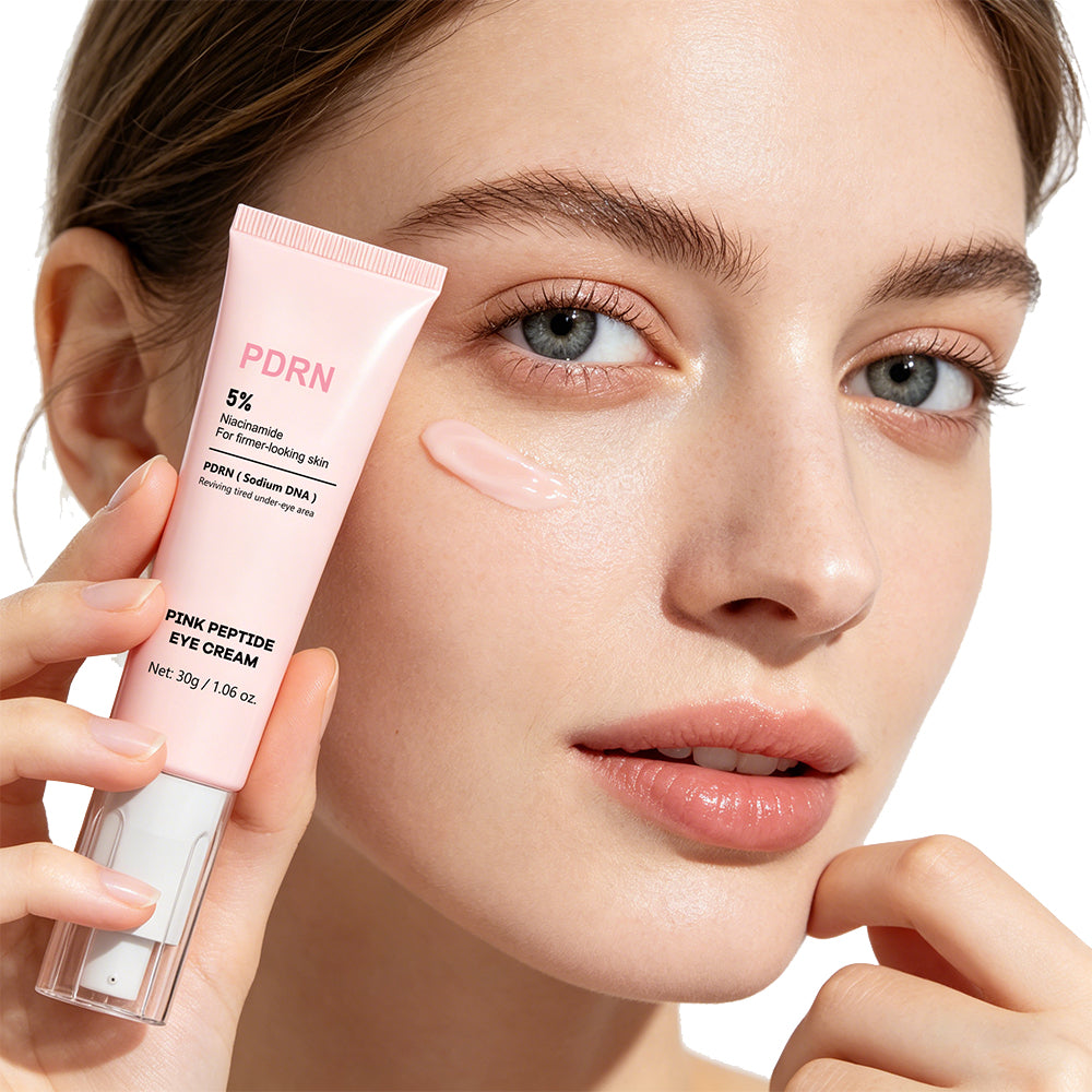 Kvinna håller PDRN Eye Cream ögonkräm intill ansiktet med en klick kräm på kinden